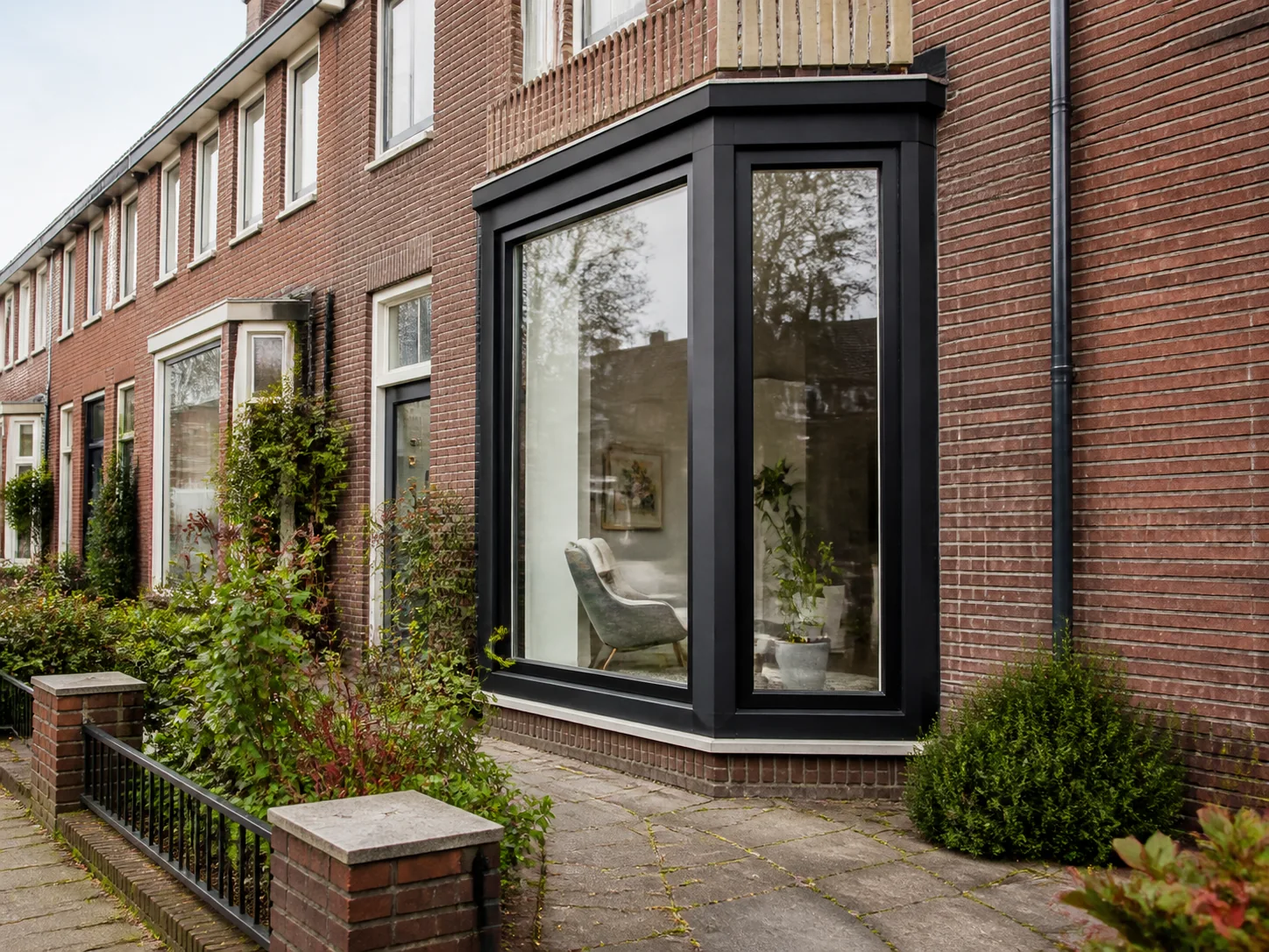 Moderne erker met slanke donkere kozijnen aan een Nederlandse rijwoning